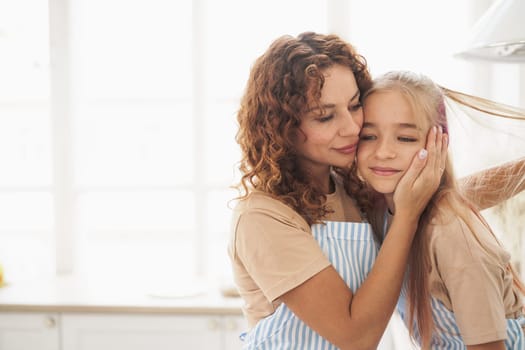 Portrait of a teen girl with her mother at home in kitchen, close up