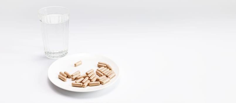 Banner Group Of Slippery Elm Capsules on plate, Glass Of Water On White Background. Traditional, dietary supplement. Holistic remedy, medication Horizontal Plane, Copy Space For Text.