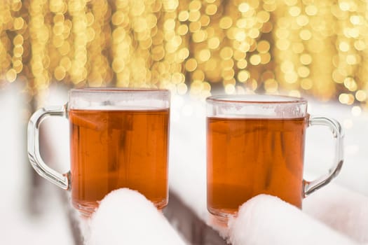 Two cups with hot tea on a  snow background