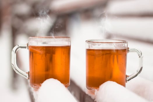 Two cups with hot tea on a  snow background