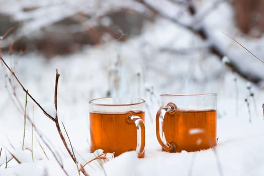 Two cups with hot tea on a  snow background