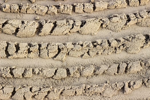 Trail from the tractor in the sand ground on the nature outdoors. Texture, background, sample