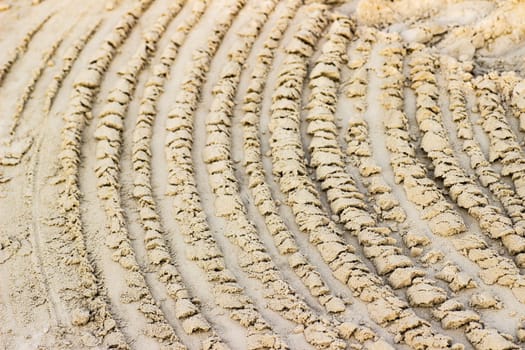 Trail from the tractor in the sand ground on the nature outdoors. Texture, background, sample