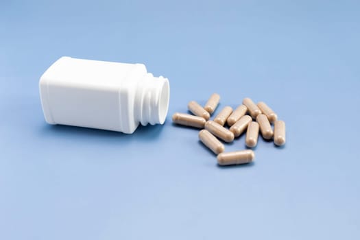 Scattered Pills, Capsules OF Slippery Elm, White Bottle, Container On Blue Background. Dietary Nutritional Supplement, Medication. Ulmus Fulva, Herbal Remedy Concept. Horizontal Plane.