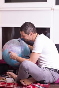 Happy man sitting and planning travel looking on the globe