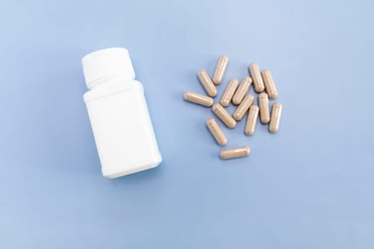 Top View Scattered Pills, Capsules OF Slippery Elm, White Bottle, Container On Blue Background. Dietary Supplement, Medication. Ulmus Fulva, Herbal Remedy Concept. Horizontal Plane.