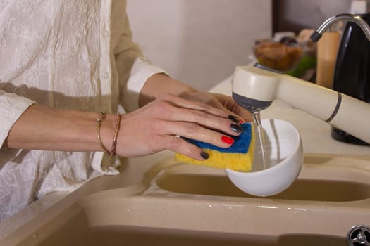 Young girl washing dishes on the kitchen, hands close up