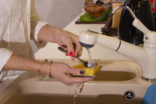 Young girl washing dishes on the kitchen, hands close up