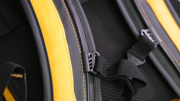 Shoulder straps in yellow and black backpack for comfortable carrying on back closeup. Orthopedic backpacks concept