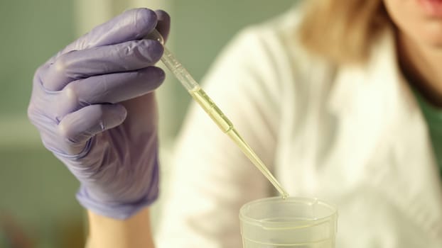 Doctor of chemical sciences in gloves dripping yellow liquid from test tube in laboratory closeup. Urine analysis concept