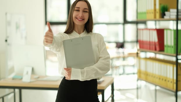 Smiling businesswoman showing ok thumb up in office. Successful career in business concept