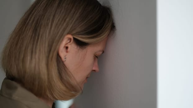 Tired depressed woman banging her head against wall. Hopeless situations concept