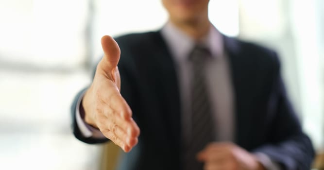 Businessman in suit extending his hand to partner for handshake closeup. Profitable dating in business concept