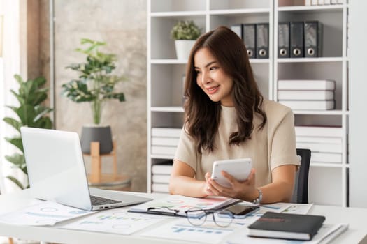 Businesswoman sits at work with laptop and computer and analyzes corporate and tax activities at office.