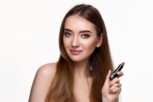beautiful young smiling woman holding pink lipstick isolated on white background