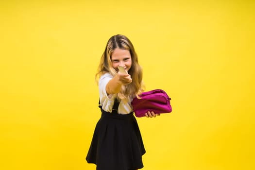 Little teenager girl with pencil case on a yellow background
