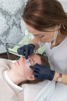 Beautician Cleans Lashes Of Young Woman With Eye Patches Before Laminating Eyelash Beauty Treatment. Curling, Staining, Extension Procedures For Lashes. Vertical Plane. Step By Step