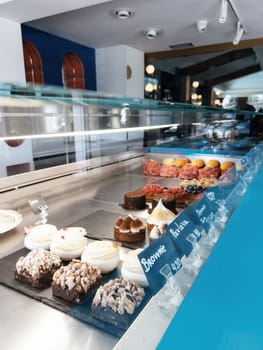 Multi-colored fresh cakes stand on the showcase of a pastry shop. High quality photo