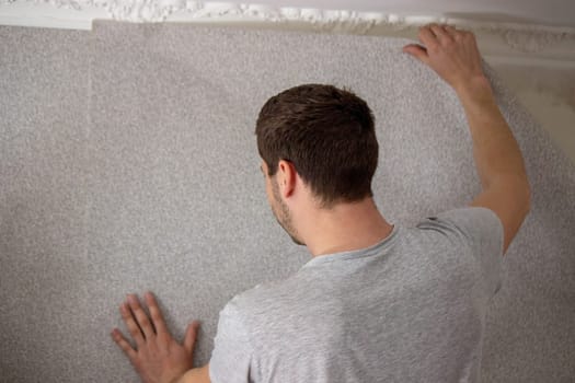 A man glues wallpaper, repairs the house. Selective focus