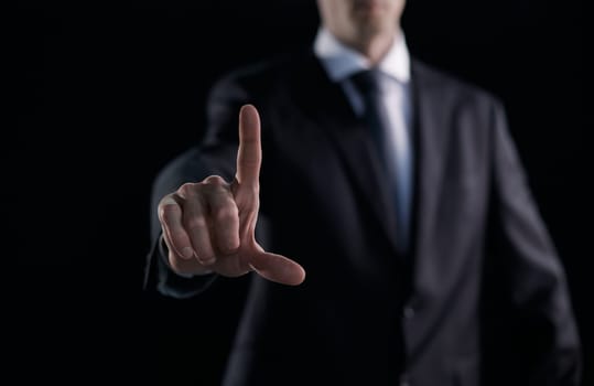 Focused businessman pointing with finger on dark background