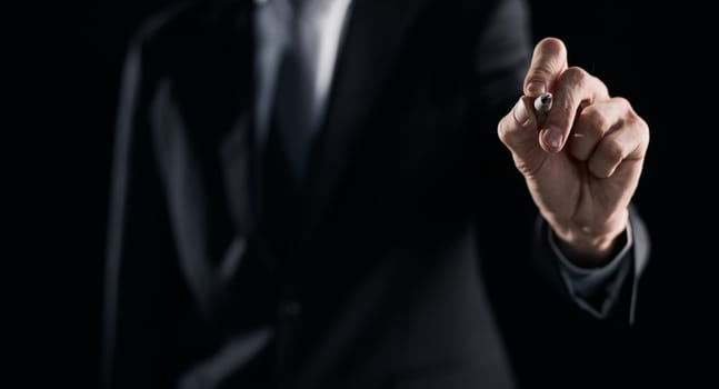 A hand holding a marker turned to the camera against a dark background