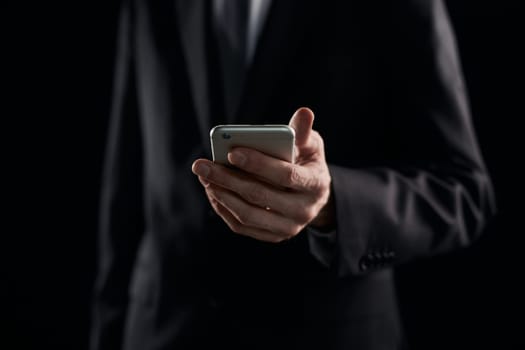 Businessman casual messaging on the phone on dark background