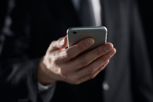 businessman looking at smartphone screen in hand on dark background