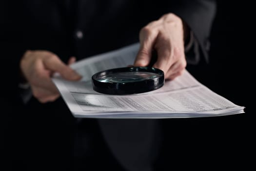 Young businessman looking to a contract through a magnifying glass