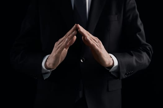 the hands of a man in a suit shows a triangle sign