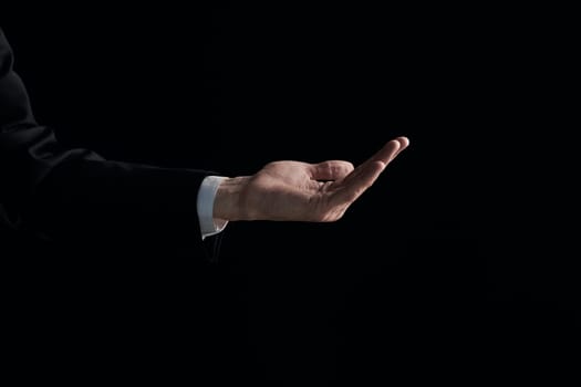 A man's hand is begging for something isolated on a black background. Palm up, close up.