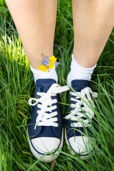 Beautiful casual shoes with flowers in socks. Flowers in blue sneakers, a classic. Walk. Modern unisex shoes. Fashionable stylish sports casual shoes. High quality photo