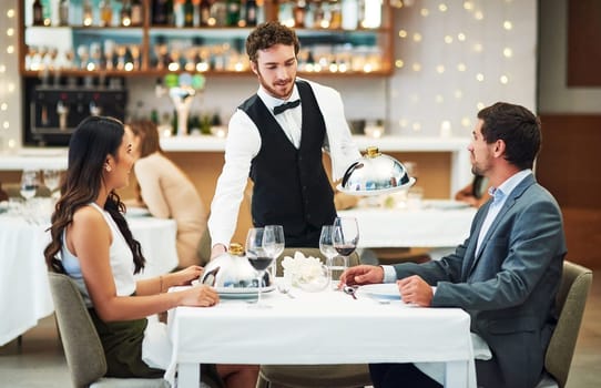 Happy couple, restaurant server and fine dining food for valentines day date, love or romance in night. Man, woman and waiter with service, party and hospitality for dinner, bonding and celebration.