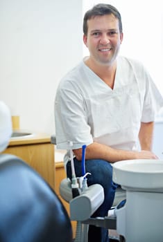 Ready for your checkup. Portrait of a male dentist sitting by the dental equipment in his office