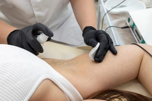 Cropped Electrologist Disinfects Client's Armpits Before Hair Removal Procedure With Medical Electrolysis Device In Beauty Salon. Horizontal Plane. Hair Removal Treatment. High quality photo