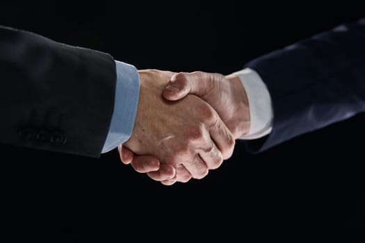 Confident businessman shaking hands on black background