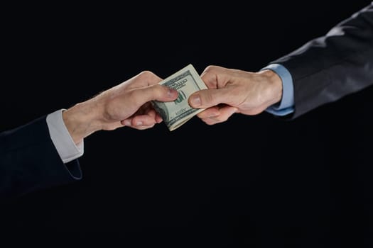 few bills in his hand on a dark background. Copyspace.