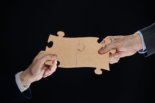 Hand holds mosaic puzzles on black background close-up. business planning teamwork concept of help strategy and success