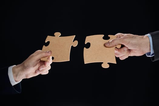 Hand holds mosaic puzzles on black background close-up. business planning teamwork concept of help strategy and success