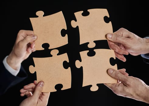 Hand holds mosaic puzzles on black background close-up. business planning teamwork concept of help strategy and success