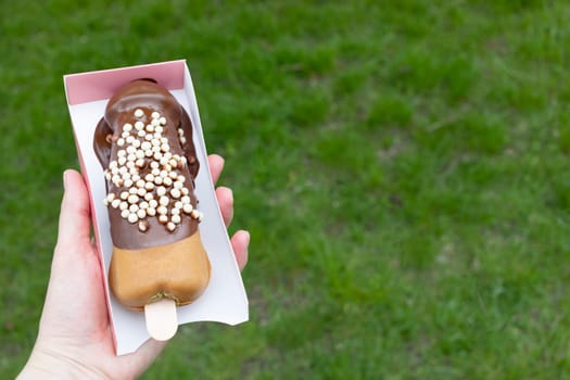 Festival Sweet Street Food Penis Shaped Waffle On Wooden Stick With Dark Chocolate, Decorated With White Air Corn Balls In Paper Box In Human Hand Outdoor. Cookie, copy space for text.Horizontal Plane