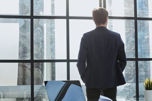 rear view.businessman standing near the office window
