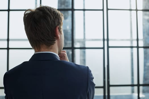 rear view.businessman standing near the office window