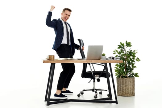 Satisfied young businessman gesturing emotionally and celebrating victory in the office