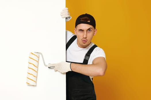 worker handyman man in working clothes painting white walls in the room. copy space for text