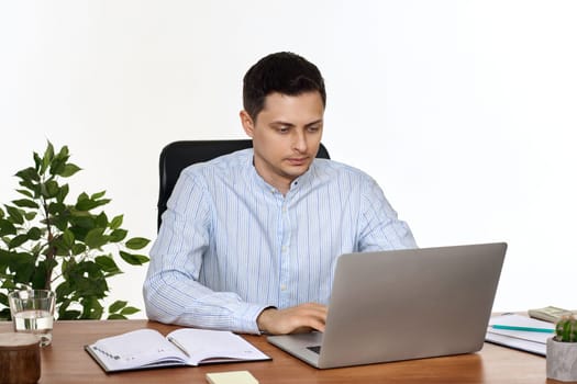 young man using laptop computer for online work at table on white background