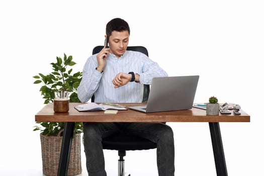 surprised businessman looking at watch while working with laptop and having phone conversation with client