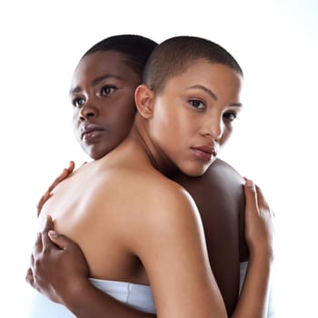 Hold me forever. Portrait of two beautiful young women holding each other while standing against a grey background