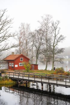 Photo of Red painted wooden traditional cafe at the autumn lake with bridge