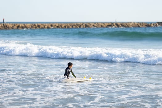 A little boy surfer in the sea. Mid shot