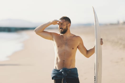 A man surfer with naked torso looking in the distance. Mid shot